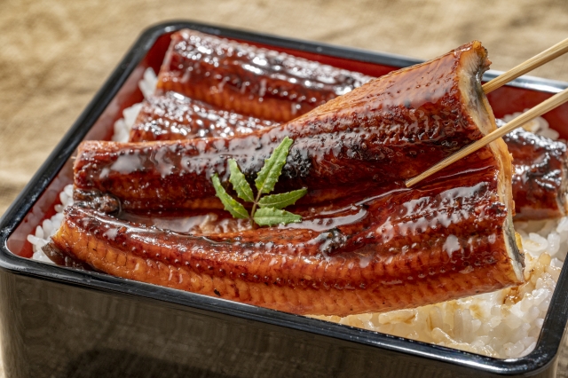 うなぎの蒲焼きを箸で持っている画像。